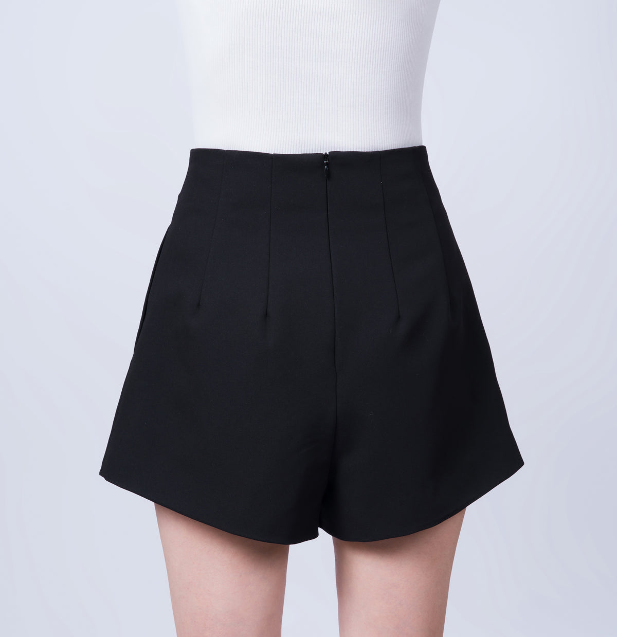 Women’s high-waisted black tailored shorts in a breathable Tencel blend. Back view featuring the smooth silhouette and tailored finish. Made in Singapore and individually finished by hand.